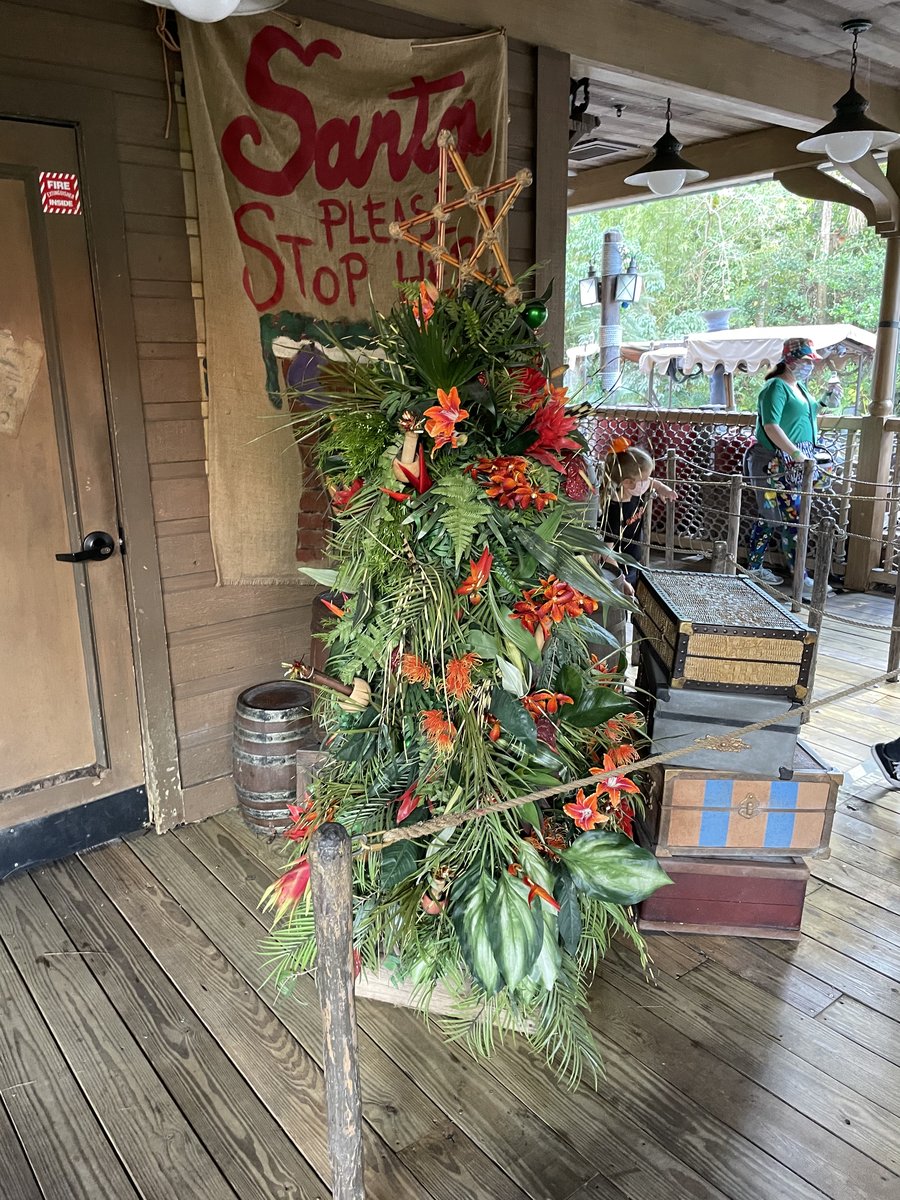 A small holiday tree decorated with tropical flowers on the Jungle Cruise loading dock