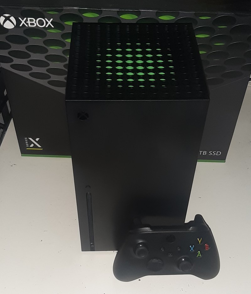 A black Xbox Series X console with a controller in front of its box
