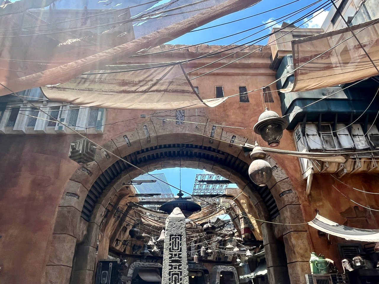 A stone archway in Black Spire Outpost with market canopies and the spire visible beyond