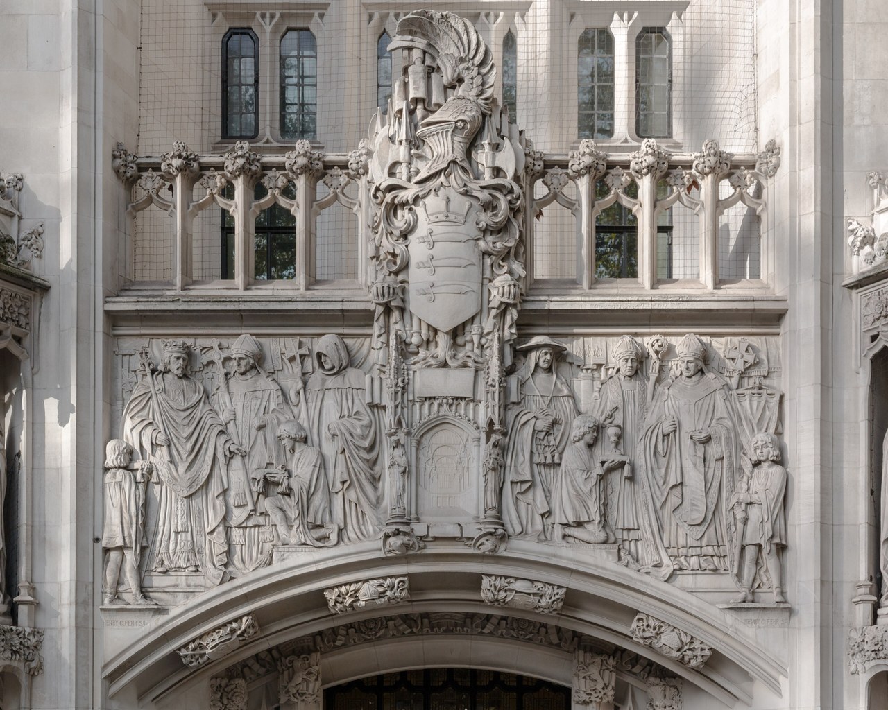 Carved stone figures and a coat of arms above the arched entrance of the UK Supreme Court building