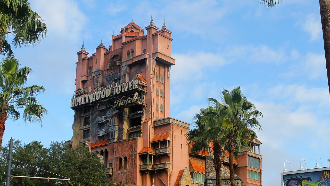 The top of the Hollywood Tower Hotel against a blue sky with palm trees in front