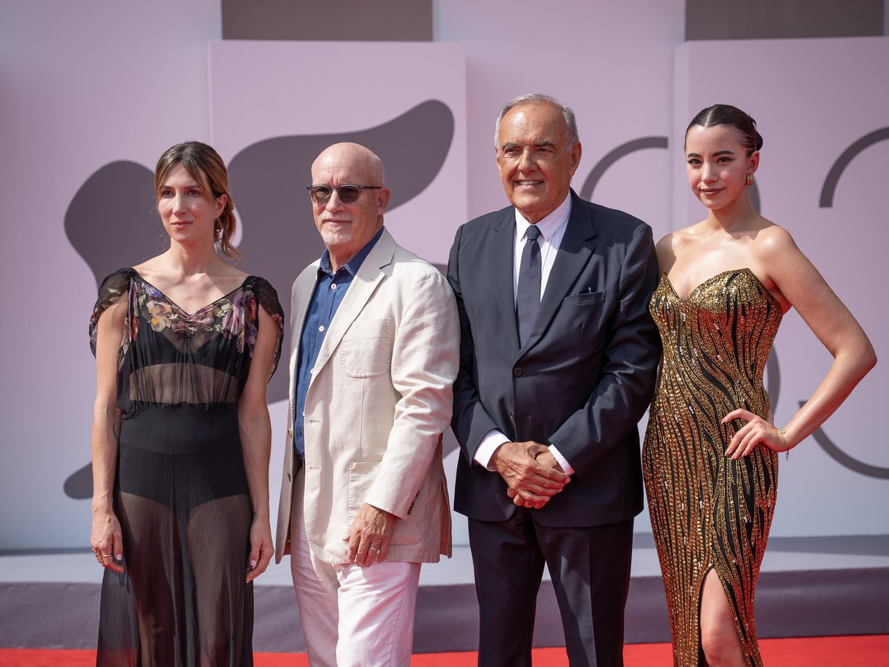 Alex Gibney posing on a red carpet with three other attendees at the Venice International Film Festival