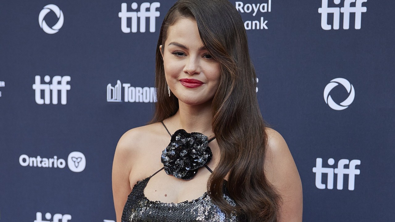 Selena Gomez smiling on the red carpet in front of a TIFF backdrop